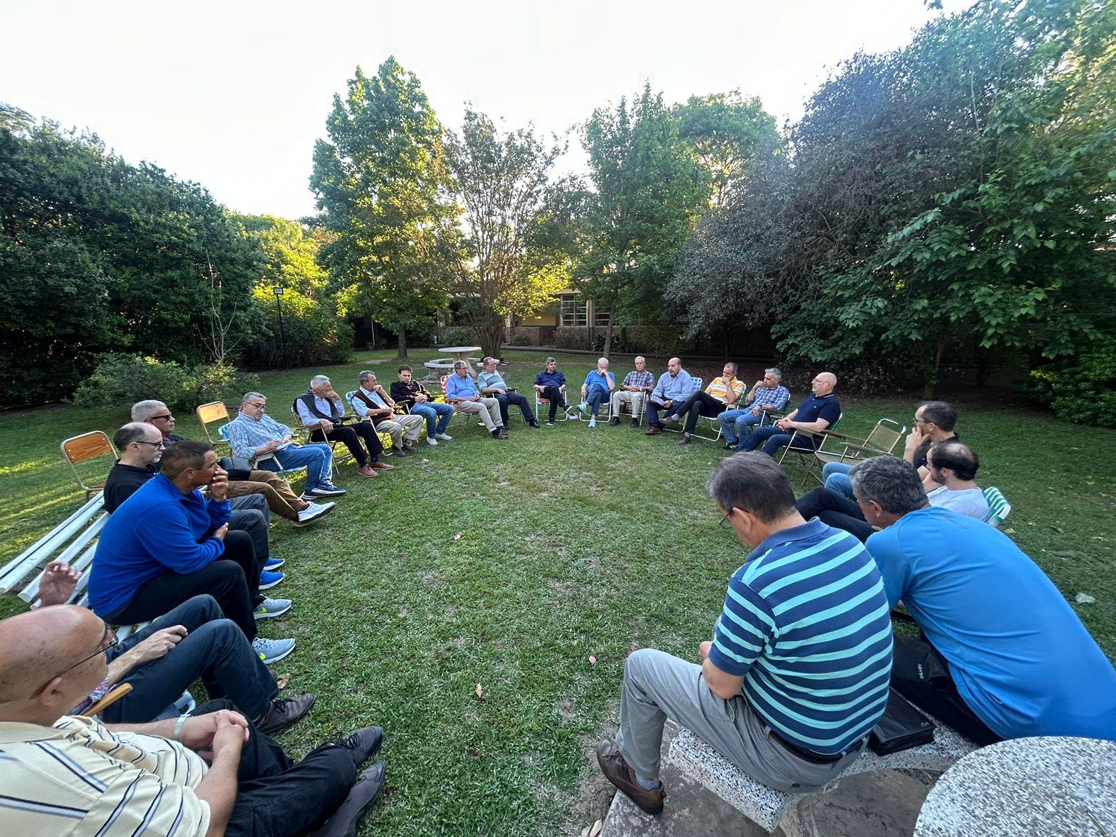 Grupo de personas conversando en ronda en el parque de una casa de retiros